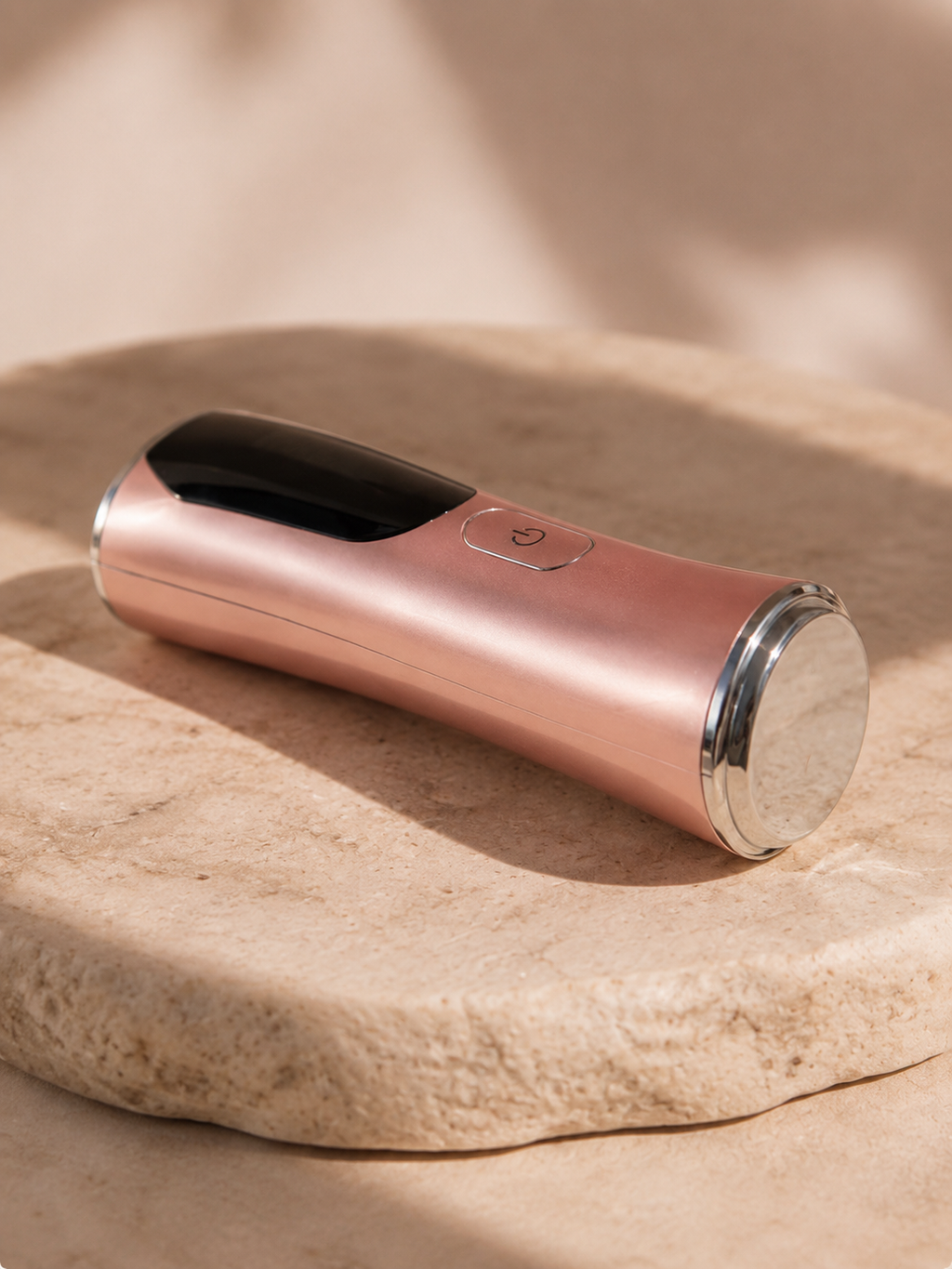 S.Rituelle Recovery Wand in Rose Gold, lying on travertine stone